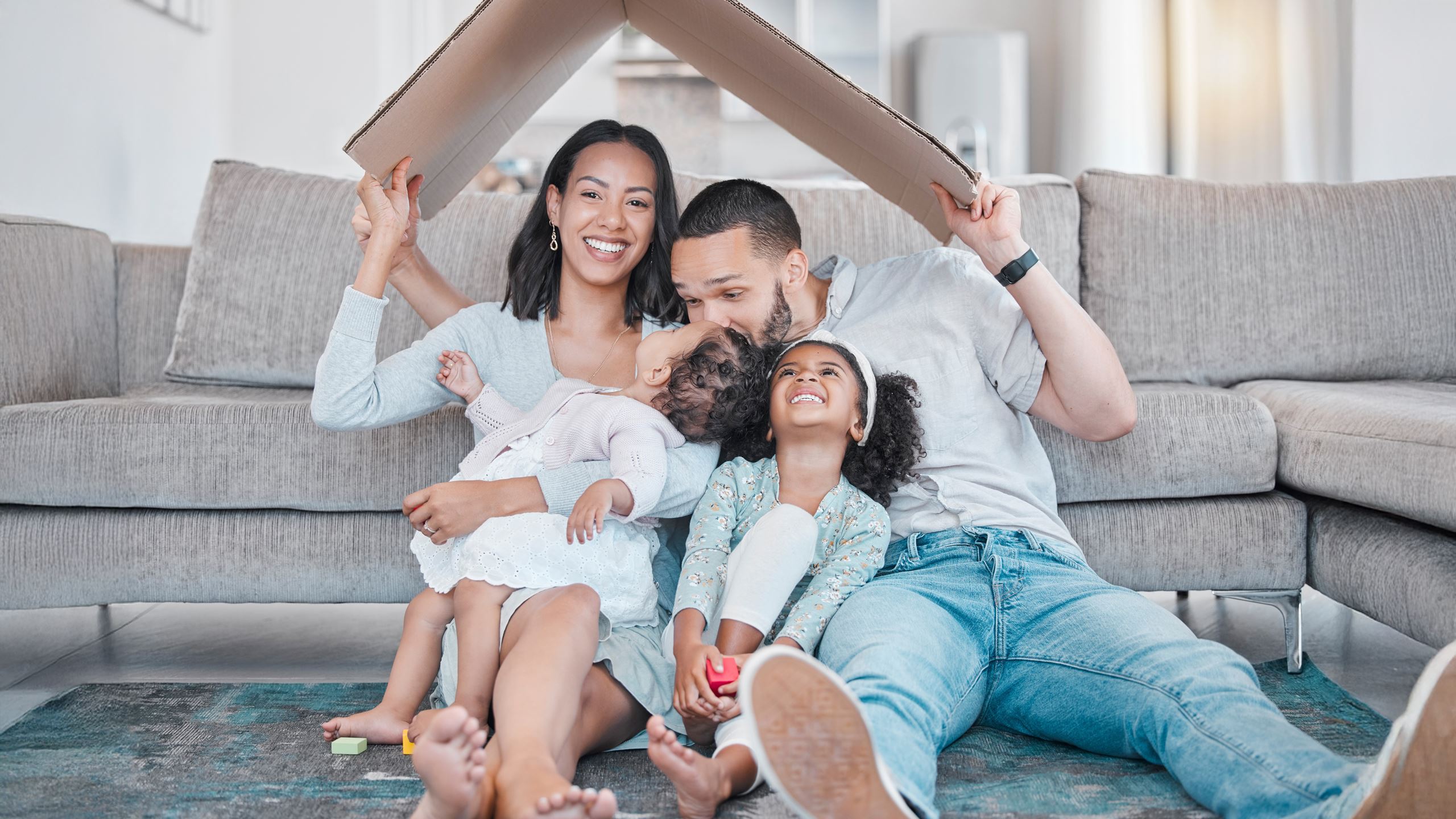 Happy family, cardboard roof or house life insurance in home living room floor in security