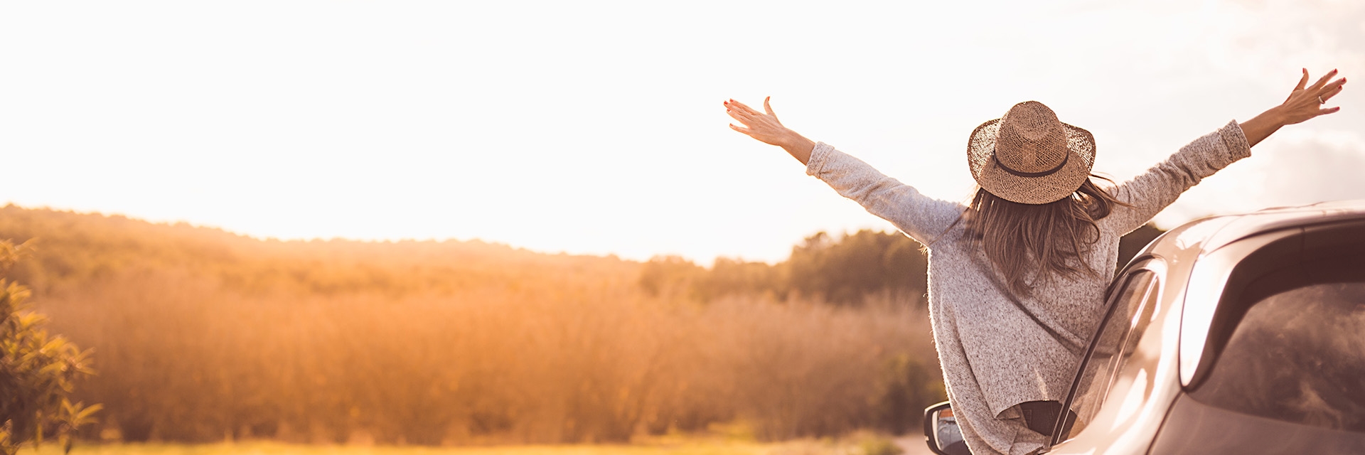 A women out of a car as they stretches her hands in the sun